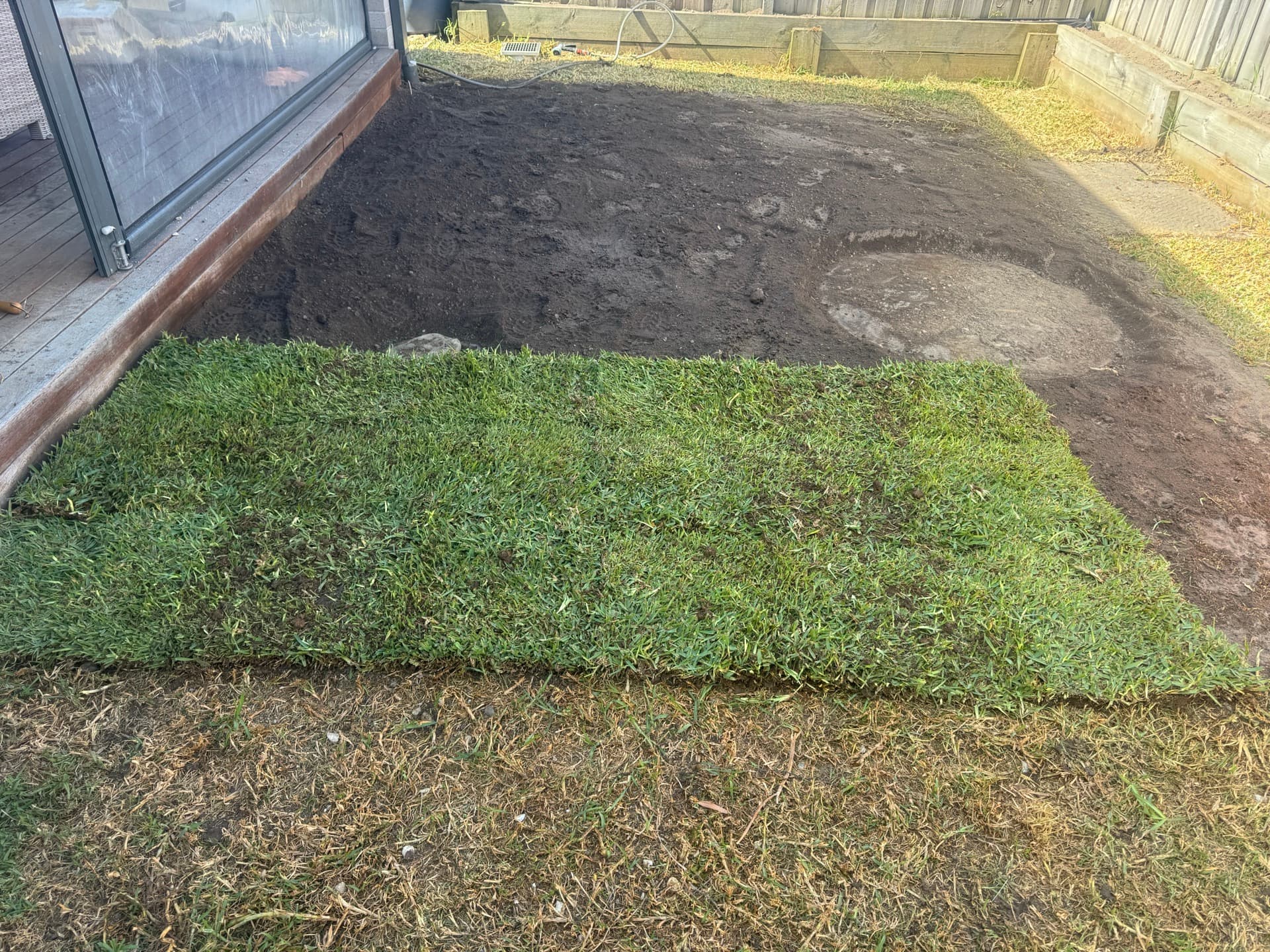 New turf rolls being laid in a backyard